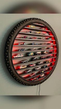 a wall mounted toy car display with red shelves and black tire rim, in the shape of a circle