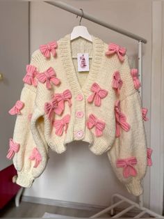 a white sweater with pink bows on it