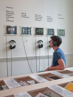 a man wearing headphones sitting at a table in front of books and listening to headphones