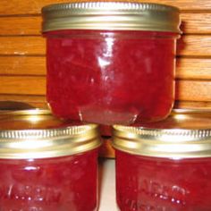 four jars filled with jam sitting on top of a table