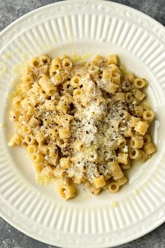 a white plate topped with pasta covered in parmesan cheese