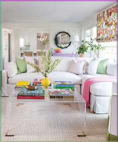 a living room filled with lots of white furniture and colorful pillows on top of it