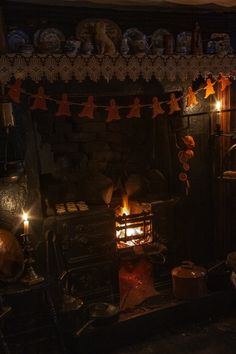 an old fashioned stove with candles lit in the dark, surrounded by other antique items