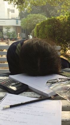 a man sleeping on top of a desk next to a calculator and pen