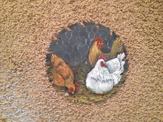 two chickens and one chicken are standing in the grass near a wire fence on a door mat