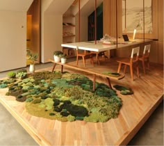 a living room filled with lots of furniture and plants on top of a wooden floor