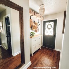 an entryway with wooden floors and white cabinets in the background is a large mirror that hangs on the wall