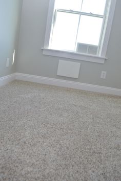 an empty room with a window and carpet