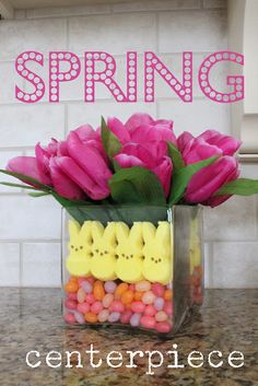 a vase filled with candy and flowers on top of a counter next to a sign that says spring centerpiece