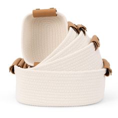 four white knitted baskets stacked on top of each other with leather handles and straps