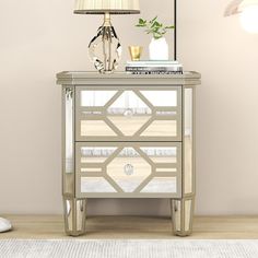 a white and silver cabinet sitting on top of a wooden floor next to a lamp