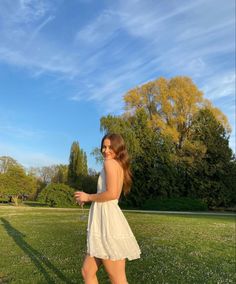 a woman in a white dress is flying a kite