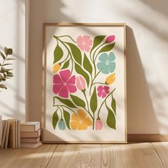 an art print with flowers on it in front of a bookshelf next to a potted plant