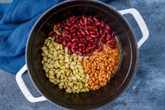 beans and other vegetables are in a pot on the ground next to a blue towel