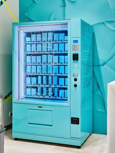 a blue vending machine sitting on top of a tiled floor next to a wall