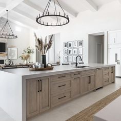 a large kitchen with an island in the middle and pictures on the wall behind it