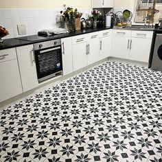 a kitchen with black and white tile flooring next to a stove top oven, sink and dishwasher