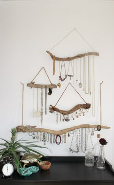 there is a wall hanging made out of branches and jewelry on the shelf next to it