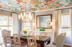 the dining room is decorated with floral wallpaper and chandeliers, along with white chairs