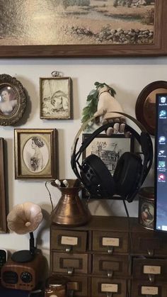 a computer monitor sitting on top of a wooden dresser next to pictures and other items