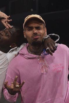 two young men one wearing a pink hoodie and the other in a white t - shirt