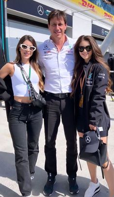 three people standing next to each other in front of a race car at the track