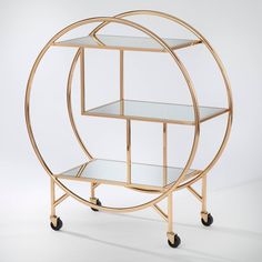 a gold metal and glass shelf with wheels on the bottom is shown in front of a white background