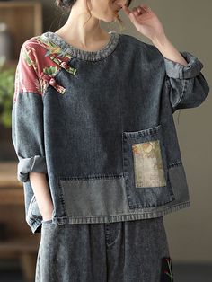 a woman wearing a jean jacket with patches on the back and side, standing in front of a wooden table