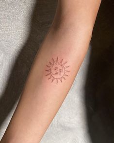 a woman's arm with a small sun tattoo on it