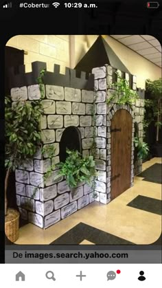 a castle made out of cardboard with plants growing on the top and doors to it