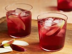 two glasses filled with red liquid and apple slices