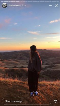 a person standing on top of a hill looking at the sun setting in the distance