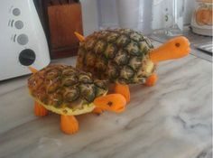 two pineapple shaped animals sitting on top of a counter next to a toaster oven