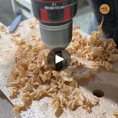 a person using a drill to cut wood shavings