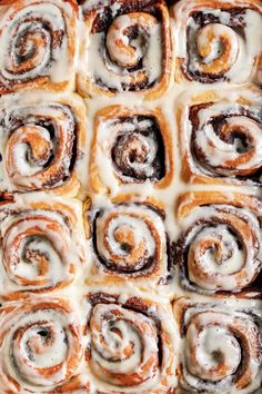 cinnamon rolls with icing sitting on top of each other in a baking pan, ready to be baked