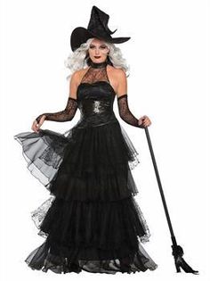 a woman in a witch costume holding a broom and wearing a black hat with white hair