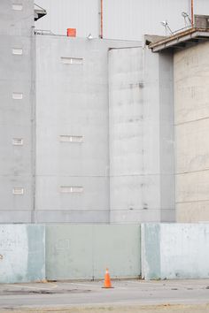 an orange fire hydrant sitting in front of two tall buildings that have silos on them