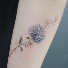 a flower tattoo on the left arm with blue and white flowers growing out of it