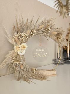 a wreath made out of dried flowers on top of a shelf next to a mirror