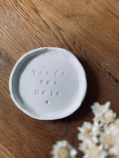 a small white plate sitting on top of a wooden table next to some dried flowers