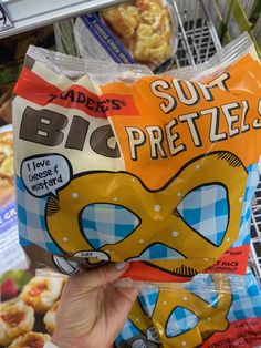 a person holding up a bag of chips in front of some other snacks on the shelf