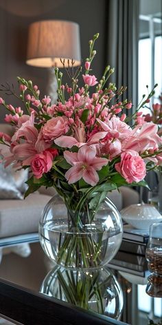 a vase filled with pink flowers sitting on top of a table next to a couch