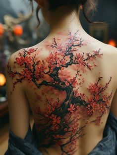 the back of a woman's body is covered in red and black ink, with a tree painted on it