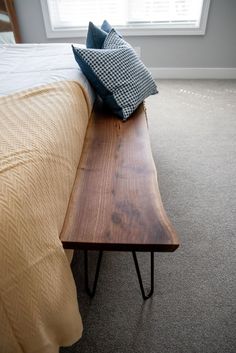 a wooden bench sitting on top of a bed next to a window