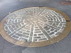 a manhole cover on the side of a sidewalk with stars and bricks in it