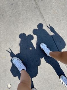 two people standing next to each other with their shadows on the ground and one person's shadow