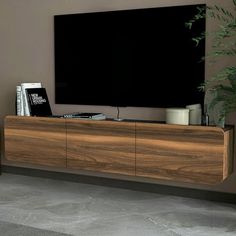 a large flat screen tv sitting on top of a wooden cabinet next to a plant