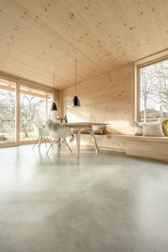 a living room filled with furniture and windows next to a wooden wall covered in wood planks