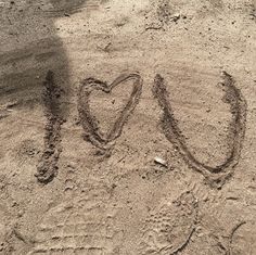 the word love is written in the sand with a heart shaped on it's side