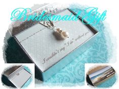 a necklace with a pearl on it sitting in a box next to an empty card